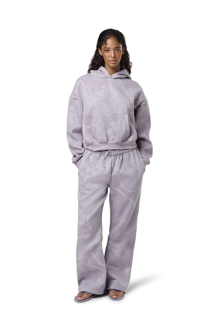 A lilac cropped hoodie with an all-over twig camouflage print, featuring a cropped relaxed fit, dropped shoulders, thick ribbed trims, and embroidered Sisters & Seekers logo.