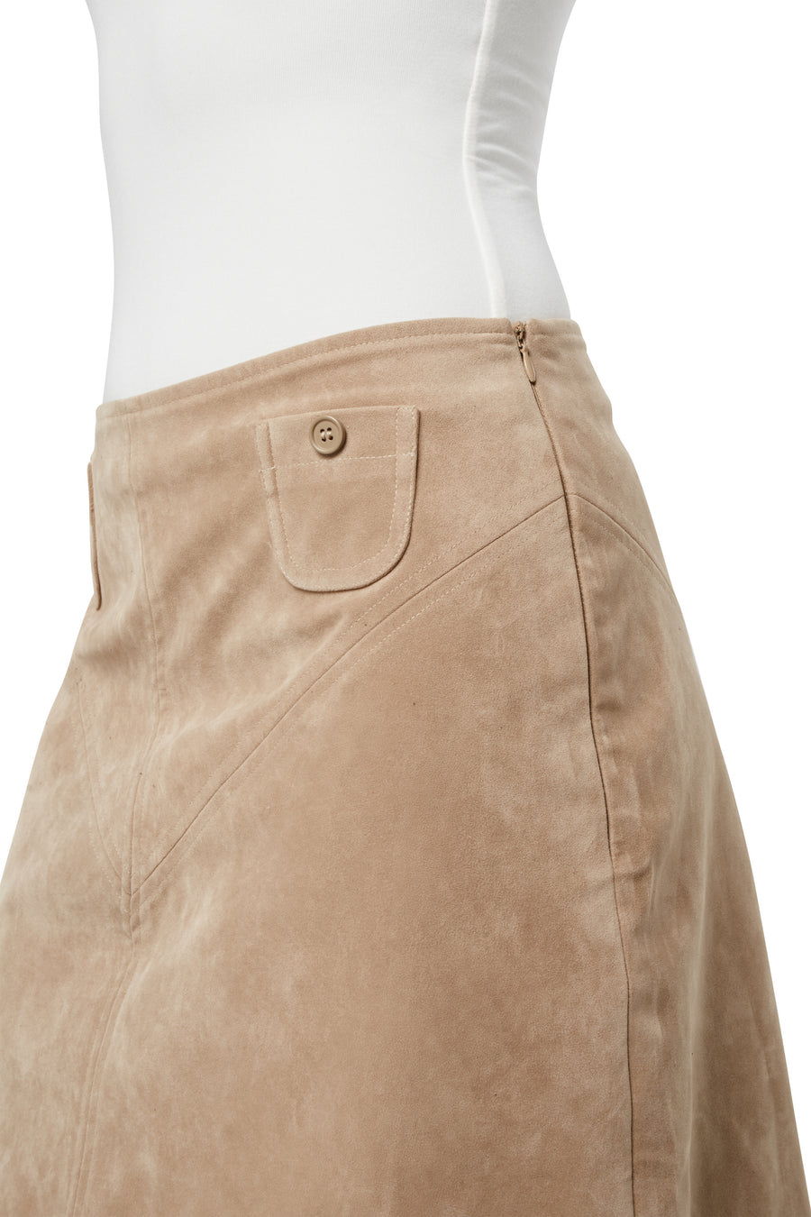 Woman wearing a fitted beige suede knee-length skirt with front flap pockets, paired with a white tank top, black flip-flop sandals, and a shell necklace.